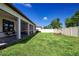A fenced backyard features lush green grass, a screened lanai, and some colorful landscaping at 16913 Clear Cork Dr, Wimauma, FL 33598