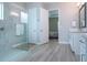 Bright bathroom featuring a glass enclosed shower with grey tiling, wood-look flooring, and access to the bedroom at 16913 Clear Cork Dr, Wimauma, FL 33598