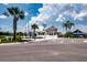 A view of the clubhouse with ample parking, featuring a manicured lawn with palm trees at 16913 Clear Cork Dr, Wimauma, FL 33598