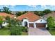Aerial view of a single-story home featuring a red tile roof, paver driveway, and lush landscaping at 16913 Clear Cork Dr, Wimauma, FL 33598