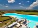 Aerial view of a community lagoon with lounge chairs, umbrellas, and cabana rentals at 16913 Clear Cork Dr, Wimauma, FL 33598