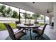A screened patio with wicker seating and a round table with wine glasses is ready for entertaining at 16913 Clear Cork Dr, Wimauma, FL 33598