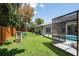 The backyard features a well-maintained lawn, wooden fence, a grill, and a screened-in pool enclosure at 1793 Pipers Meadow Dr, Palm Harbor, FL 34683