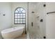 Bright bathroom features a soaking tub under an arched window, alongside a sleek glass-enclosed shower with pebble floor at 1793 Pipers Meadow Dr, Palm Harbor, FL 34683