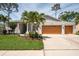 Charming single-story home with well-manicured lawn, palm trees, and a three-car garage at 1793 Pipers Meadow Dr, Palm Harbor, FL 34683