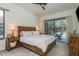 Bright main bedroom features a rustic wood bed frame and sliding door to the pool and outdoor seating area at 1793 Pipers Meadow Dr, Palm Harbor, FL 34683