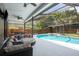 Screened in pool area with large sectional sofa, ceiling fans and lush landscaping at 1793 Pipers Meadow Dr, Palm Harbor, FL 34683