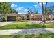 Charming one-story brick home featuring an attached garage, mature trees, and lush landscaping with a stone walkway at 1807 Tawnee Pl, Brandon, FL 33510