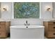 Bright bathroom featuring a standalone tub with window view and double sinks with wood cabinetry at 1903 S Cardenas Ave, Tampa, FL 33629