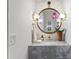 Elegant powder room featuring a round mirror, sconces, and gray countertop with white brick accent wall at 1903 S Cardenas Ave, Tampa, FL 33629