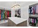 Spacious walk-in closet with custom shelving, storage island, marble countertop, modern chandelier, and ample storage at 1903 S Cardenas Ave, Tampa, FL 33629