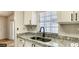 Galley-style kitchen featuring granite countertops, stainless steel sink and white cabinetry at 2007 W De Leon St # C, Tampa, FL 33606