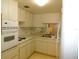 Efficient kitchen featuring white cabinets, appliances, and a mirrored backsplash at 2449 Columbia Dr # 53, Clearwater, FL 33763