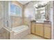 Elegant bathroom featuring travertine walls, soaking tub, and modern vanity with granite countertop at 2863 Duncan Tree Cir, Valrico, FL 33594