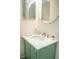 Bathroom vanity with marble countertop, round mirror, and green painted cabinet base with louvered doors at 340 81St Ave, St Pete Beach, FL 33706