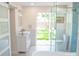 Bright bathroom featuring a white vanity, glass enclosed shower, soaking tub, and outdoor view at 340 81St Ave, St Pete Beach, FL 33706