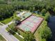 Aerial view of community tennis courts surrounded by lush greenery and a serene pond at 3885 Timber Ridge Ct, Palm Harbor, FL 34685