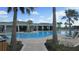 An in-ground community pool is surrounded by mature palm trees, a large outdoor seating area, and lounge chairs at 4114 Dovetail Ln, Palmetto, FL 34221