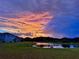 Scenic view of a pond reflecting a vibrant sunset, adjacent to well-maintained homes and a verdant lawn at 4114 Dovetail Ln, Palmetto, FL 34221