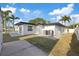A modern home exterior with a manicured lawn and lush tropical palm trees at 504 Driftwood E Dr, Palm Harbor, FL 34683