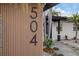 Close up of a home featuring wood facade with home address and well-manicured tropical landscaping at 504 Driftwood E Dr, Palm Harbor, FL 34683