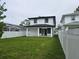 Expansive backyard showcasing a modern two-story home with white fencing and a lush green lawn at 5730 66Th Ln N, St Petersburg, FL 33709