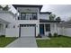 Two-story home with white exterior, black trim, balcony, blue front door, well-kept lawn and driveway at 5730 66Th Ln N, St Petersburg, FL 33709