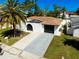 Charming home featuring an arched entrance, two-car garage, and a well-maintained lawn with a mature palm tree at 6311 Seabreeze Dr, Port Richey, FL 34668