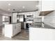 Bright kitchen showcasing white cabinetry, stainless steel appliances, granite countertops, and wood-look flooring at 6311 Seabreeze Dr, Port Richey, FL 34668