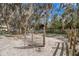 Equestrian facility with white sand area and paddock featuring mature trees and metal gated fencing under a bright blue sky at 6718 Watson Rd, Riverview, FL 33578