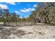 White sand equestrian paddock features mature trees and round pen fencing under a bright blue sky with white puffy clouds at 6718 Watson Rd, Riverview, FL 33578
