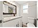 Clean bathroom featuring granite counters, white cabinets, a large mirror, and a window at 7134 2Nd N St, St Petersburg, FL 33702