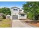 Two-story house with gray garage door, shed, tidy landscaping, and lots of shade trees at 7134 2Nd N St, St Petersburg, FL 33702