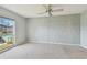 Empty bedroom featuring a ceiling fan and a large window with a view of the community pool at 8703 Bardmoor Blvd # 203, Seminole, FL 33777
