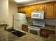 Classic kitchen featuring wood cabinets, granite countertops, and white appliances at 10114 Winsford Oak Blvd # 517, Tampa, FL 33624
