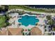 Overhead view of a uniquely shaped pool surrounded by sun loungers, tropical landscaping, and community amenities at 1102 Emerald Dunes Dr, Sun City Center, FL 33573