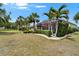 Spacious backyard overlooking lush greenery, accented by palm trees and a cozy screened lanai with a red umbrella at 1102 Emerald Dunes Dr, Sun City Center, FL 33573