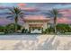 Elegant community entrance with a grand portico, palm trees, and lush landscaping under a vibrant sky at 1102 Emerald Dunes Dr, Sun City Center, FL 33573