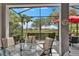 Relaxing screened-in lanai overlooking scenic views, featuring comfortable seating and a red umbrella for shade at 1102 Emerald Dunes Dr, Sun City Center, FL 33573