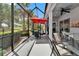 Screened lanai with outdoor seating under an umbrella, ceiling fan, and view of green landscape at 1102 Emerald Dunes Dr, Sun City Center, FL 33573