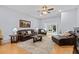 Well-lit living room featuring hardwood floors, ceiling fan, a fireplace, comfortable leather furniture, and access to the lanai at 1216 Bensbrooke Dr, Wesley Chapel, FL 33543
