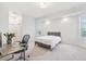 A light-filled bedroom has a bed with a gray upholstered headboard and includes a workstation with a gray desk and chair at 13096 Linzia Ln, Spring Hill, FL 34609