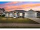 Charming single-story home with manicured lawn and neutral stucco exterior under a vibrant, colorful sunset sky at 13096 Linzia Ln, Spring Hill, FL 34609
