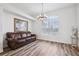 Bright living room featuring wood floors, a modern chandelier, and a comfortable leather couch at 13096 Linzia Ln, Spring Hill, FL 34609