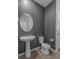 Charming powder room with gray walls, wood-look tile flooring, and pedestal sink at 13821 Kinsale St, Riverview, FL 33579