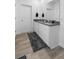 Bright bathroom featuring dual sinks, white cabinets, wood look tile floors, and a large mirror at 13821 Kinsale St, Riverview, FL 33579
