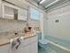 Bathroom with white tile shower, blue toilet, and vessel-patterned wallpaper at 14006 79Th Ave, Seminole, FL 33776