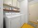 Bright laundry room with white washer and dryer, storage cabinets, and yellow tile flooring at 14006 79Th Ave, Seminole, FL 33776