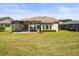 Wide backyard with a screened lanai, a lush green lawn, and mature landscaping at 14209 Quintessa Ln, Lithia, FL 33547