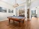 Well-lit game room with a pool table, hardwood floors, decorative wood wall, and view into living space at 14209 Quintessa Ln, Lithia, FL 33547